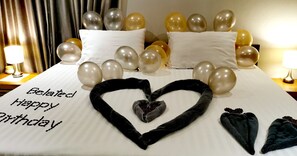 A bed with a heart-shaped arrangement of black pillows and a note saying "Belated Happy Birthday". - Naiharn Beach Resort (Rawai)