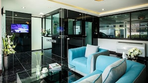 A modern lobby with a reception desk, seating area, and a television. - Chonlada Place (Chiang Mai)
