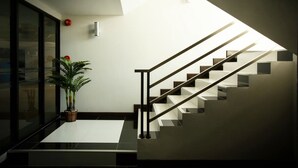 A modern staircase with a geometric design, a potted plant, and a glass door. - Chonlada Place (Chiang Mai)