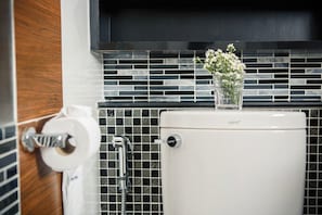 A bathroom with a toilet, a shower, and a tiled backsplash. - Chonlada Place (Chiang Mai)