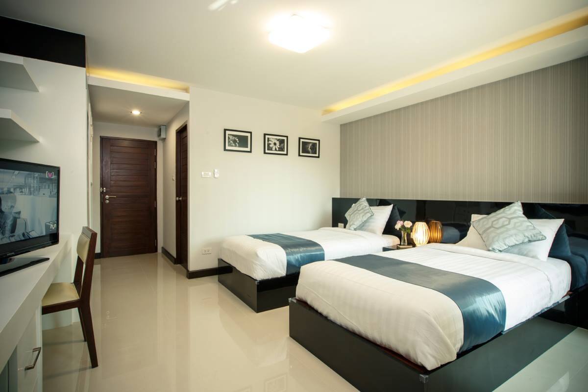 A hotel room with two beds, a TV, and a desk.