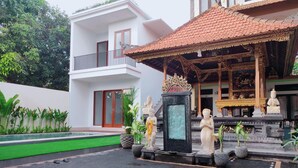A temple with statues, a pool, and a building with a balcony. - Pondok Denayu Homestay (Kuta)