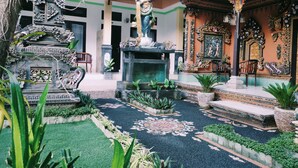 An ornate courtyard with a statue, intricate wall decorations, and a fountain. - Pondok Denayu Homestay (Kuta)