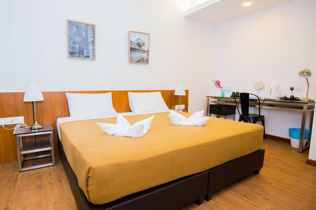 A hotel room with a large bed, two bedside tables, a desk, and a chair.