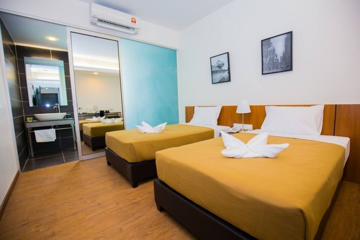 A hotel room with two beds, a bathroom with a sink and mirror, and a cityscape view.