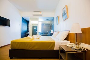 A hotel room with a bed, bedside table, lamp, and a TV mounted on the wall. - Urban Inn Kulim (Kulim)