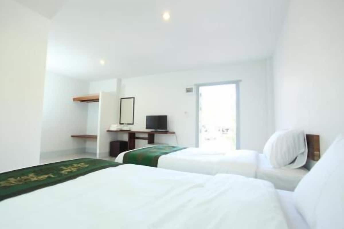 A hotel room with two beds, a desk, a television, and a door leading to a balcony.