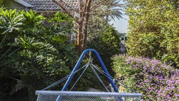 Relax in a hammock suspended between two trees, surrounded by lush plants and a serene garden view.