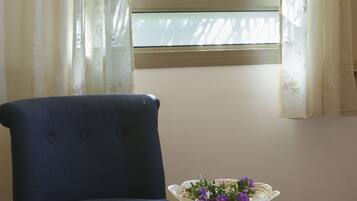 A room with a window, a chair, and a table with a decorative bowl.