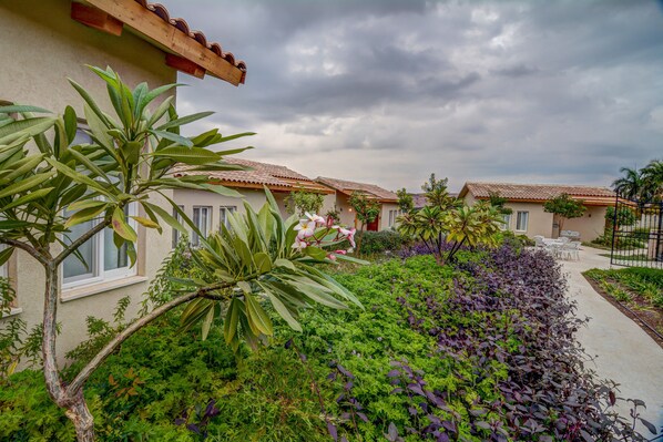 Una hilera de villas con un jardín al frente, un camino y vistas al cielo.