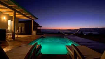 A swimming pool with a view of the mountains at dusk.