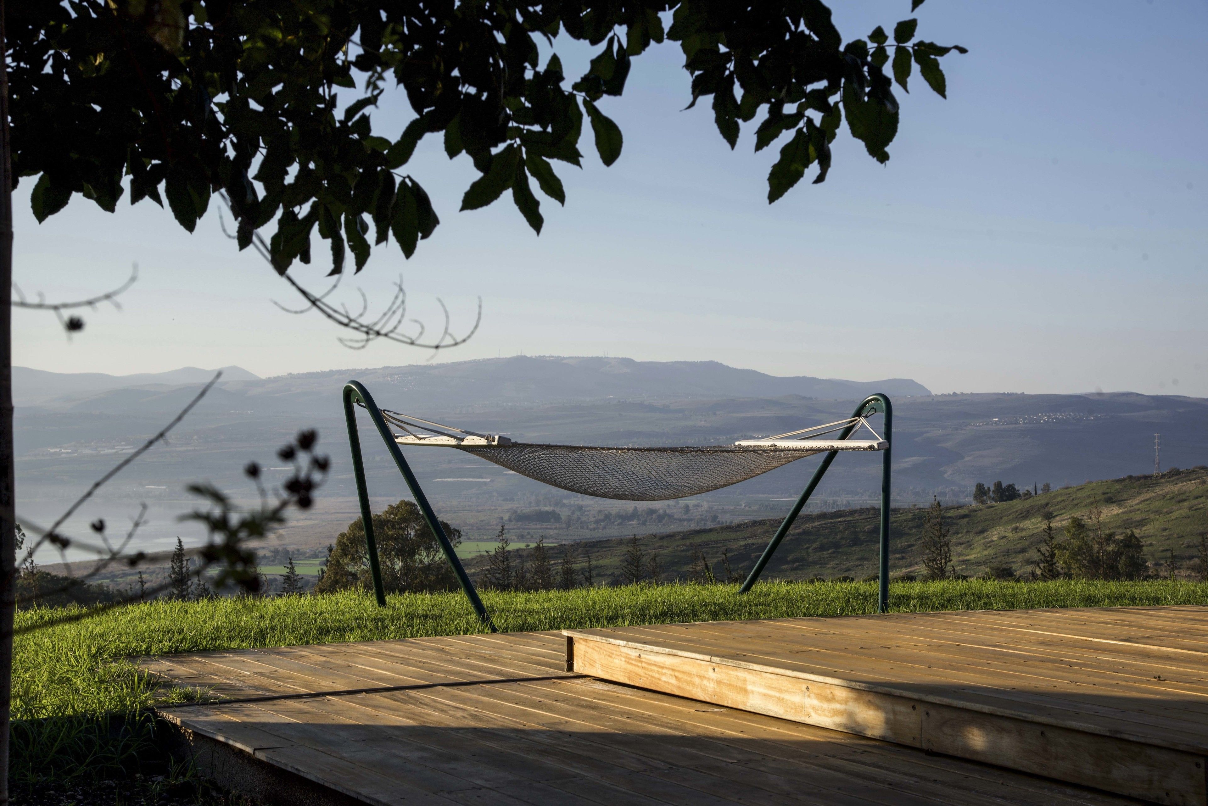 A hammock on a wooden deck overlooking a mountainous landscape.