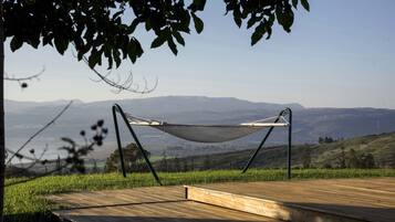A hammock on a wooden deck overlooking a mountainous landscape.