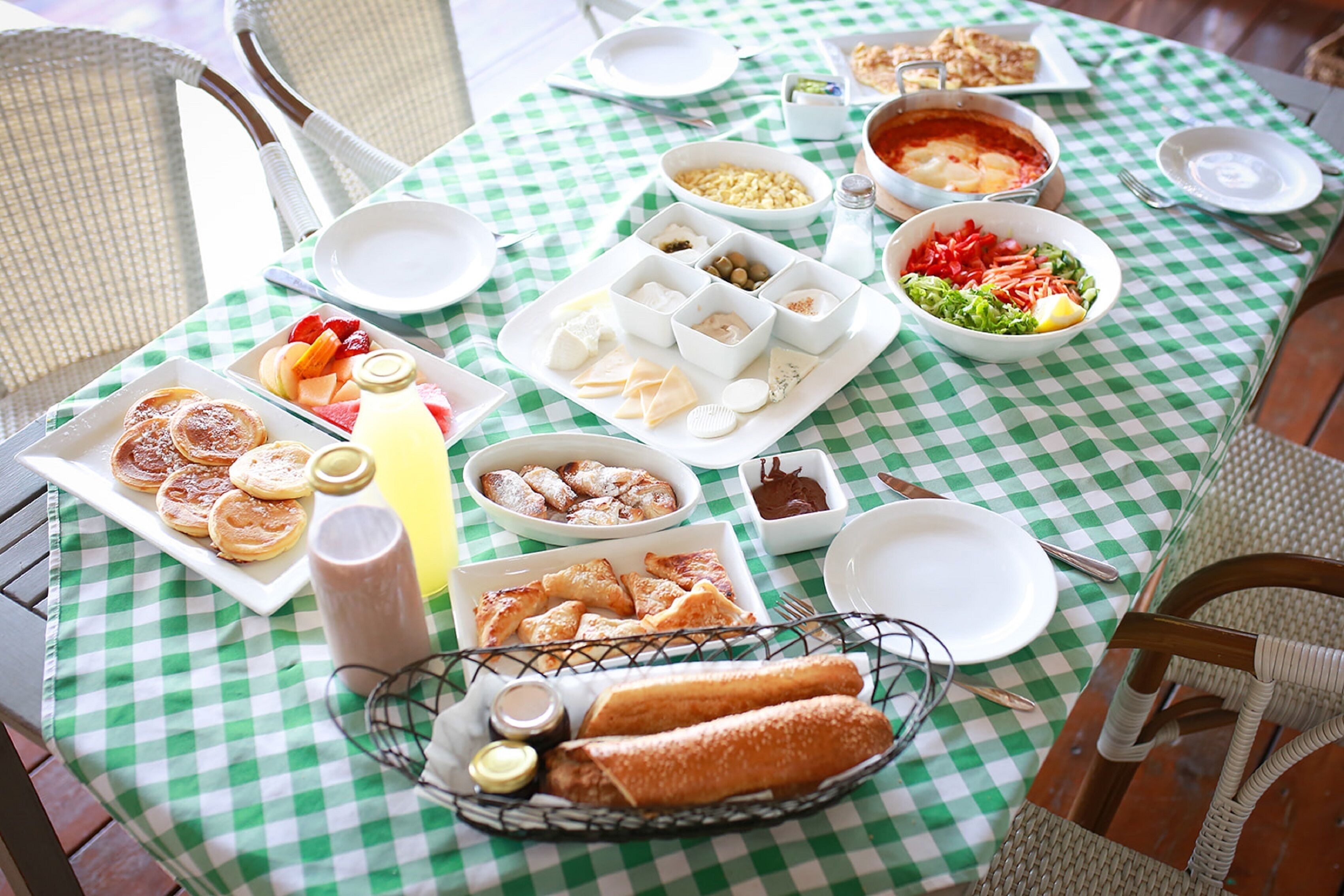 Ein Tisch gedeckt mit verschiedenen Speisen, darunter Brot, Käse und Salate, was auf eine Mahlzeit hindeutet.