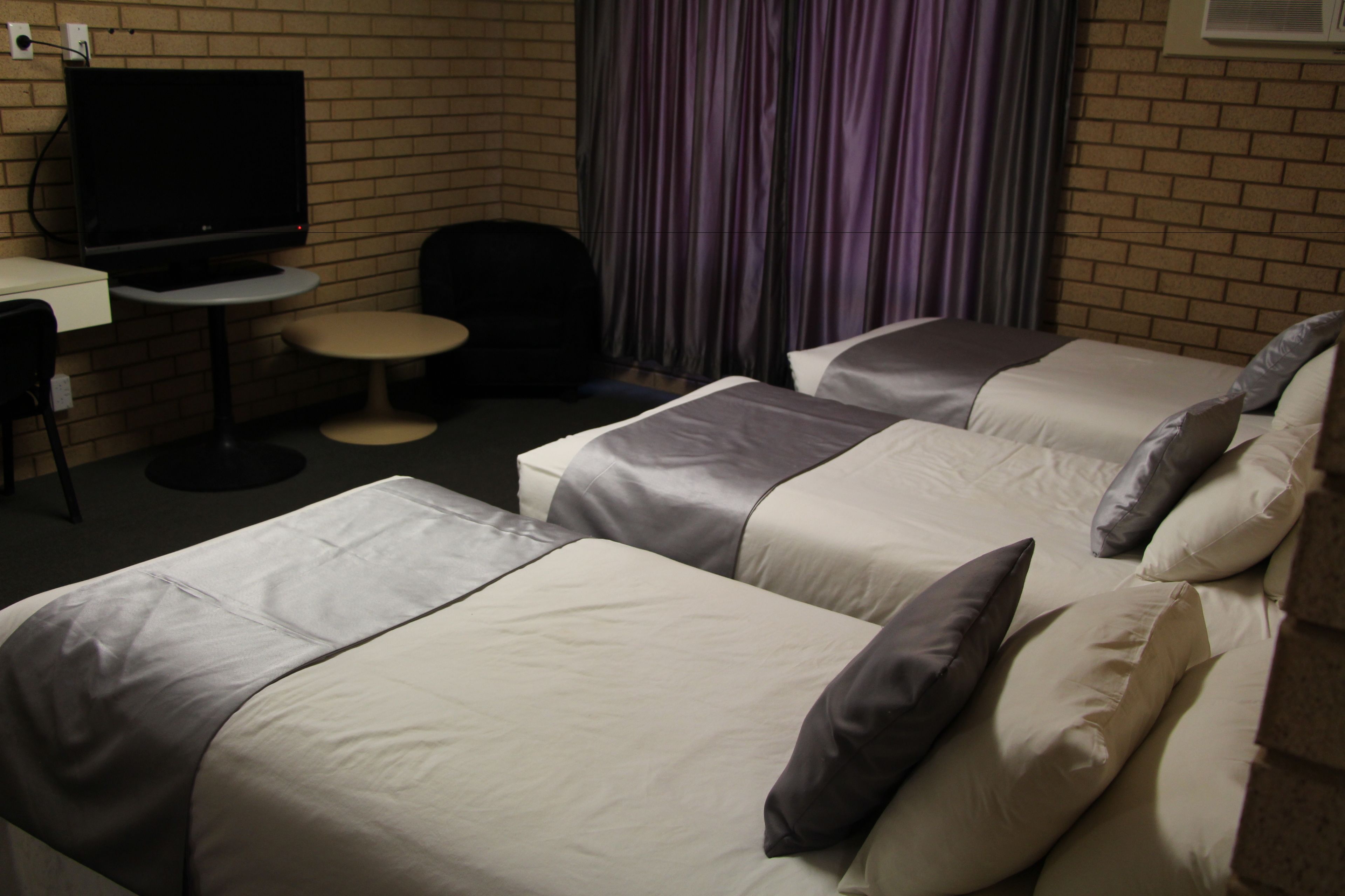 A hotel room with two beds, a TV, a small table, and a chair.