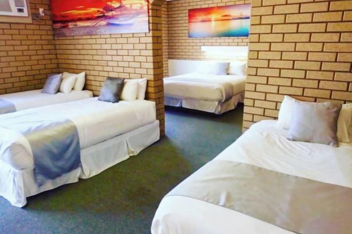 Ett hotellrum med två separata sängar, en tegelvägg och en tavla.