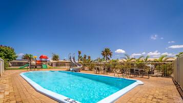 Relax by the pool surrounded by a patio and a children's play area.