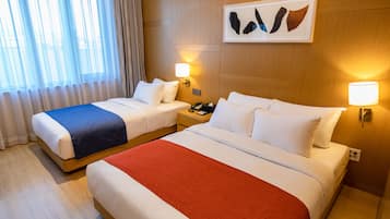 A hotel room with two beds, a large window with curtains, a wall-mounted artwork, and bedside lamps.