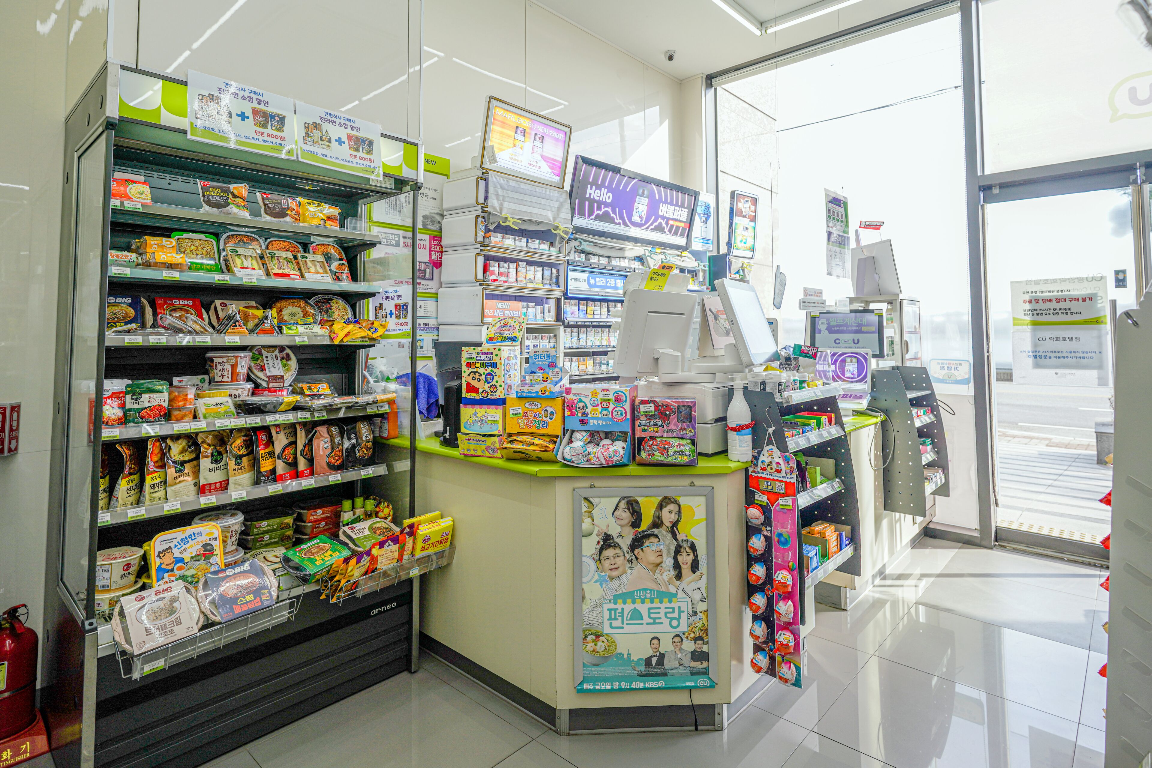 A brightly lit convenience store with shelves stocked with snacks, drinks, and household items.