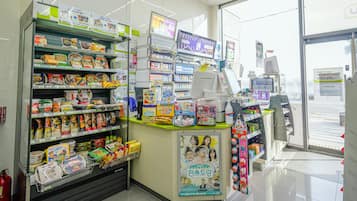 A brightly lit convenience store with shelves stocked with snacks, drinks, and household items.
