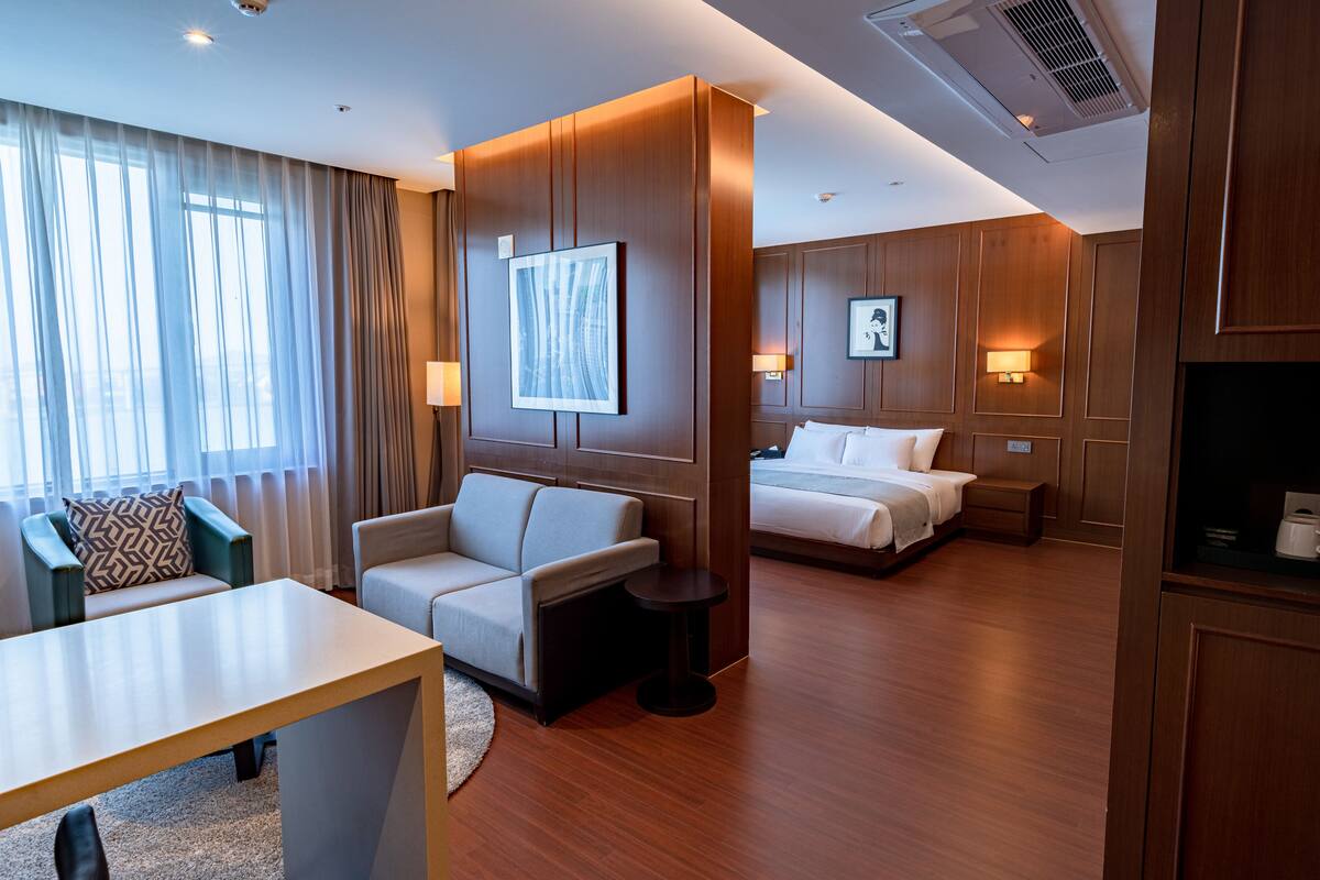 A hotel room with a sofa, a bed, a desk, and a view of the outdoors.