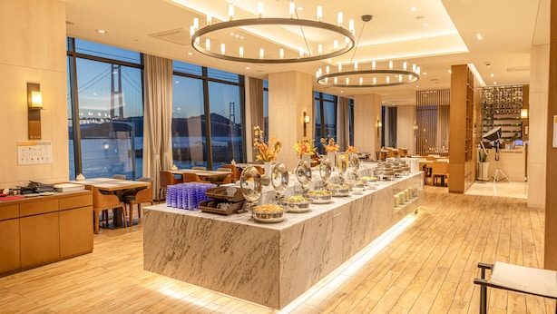 A modern hotel lobby with a marble reception desk, dining area, and large windows offering a view of a bridge. - Hotel Lacky Gwangyang (Gwangyang)