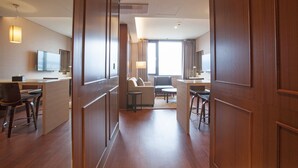 A modern hotel room with a wooden floor, a sofa, a dining area, and a TV. - Hotel Lacky Gwangyang (Gwangyang)