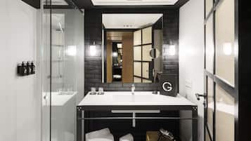 A modern bathroom with a glass shower enclosure, a large mirror, and a built-in sink.