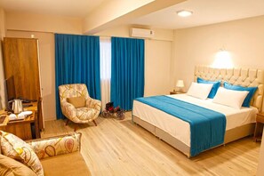 A hotel room with a bed, a chair, a desk with a kettle, and a wardrobe. - Fayton Hotel (Akhisar)