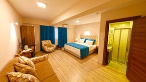 Una habitación de hotel con cama, sofá, sillón, escritorio y baño.