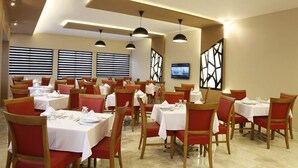 Un comedor con varias mesas y sillas, luces en el techo y un televisor en la pared.