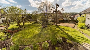 Un jardin bien entretenu, avec une pelouse, des arbres et un espace patio.