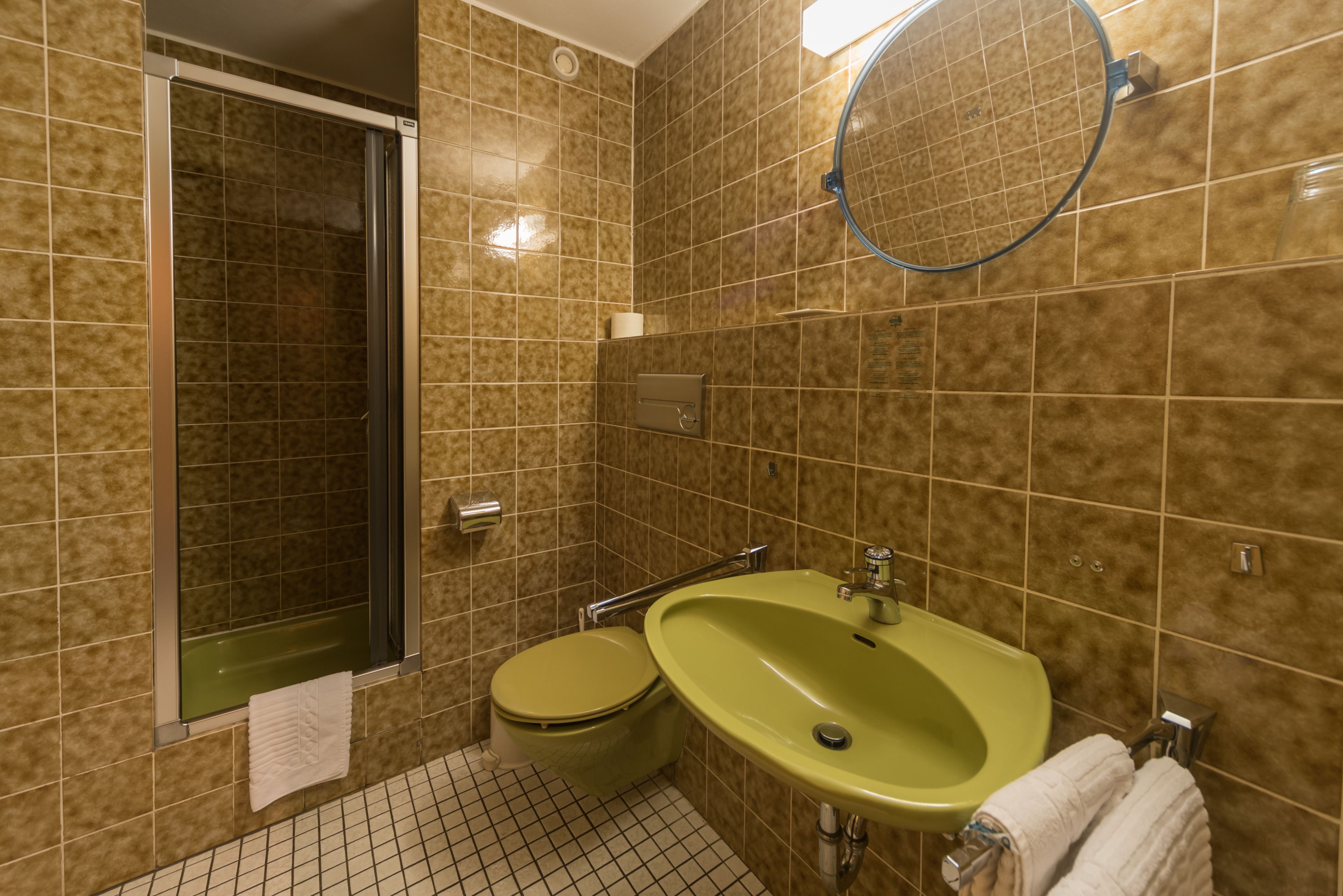 A bathroom with a shower, toilet, sink, and a mirror.