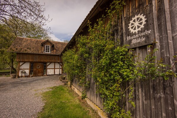 Un bâtiment en bois avec une enseigne indiquant « Historische Mühle » et un symbole de roue.