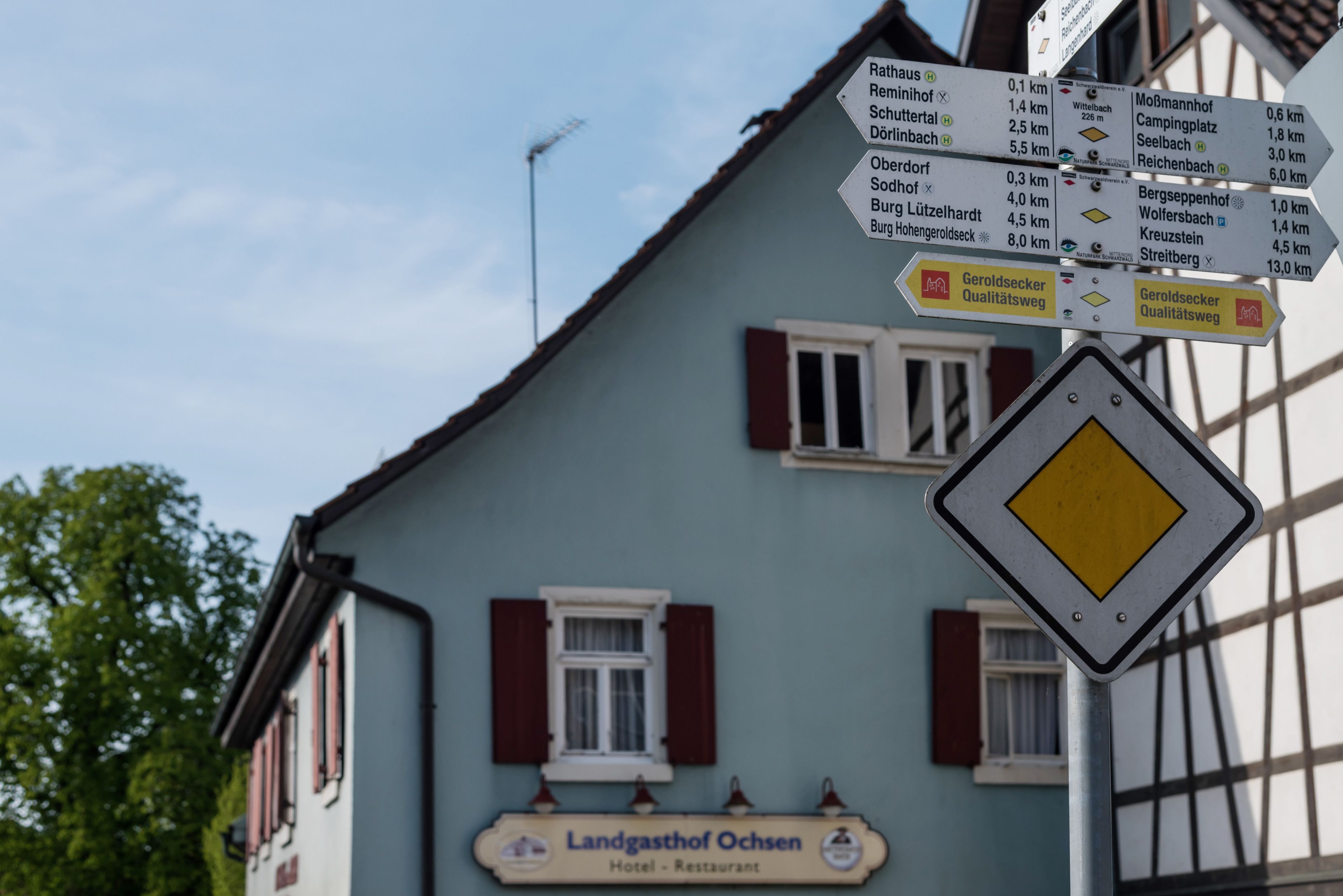 A directional signpost in front of a building with a sign for 'Landgasthof Ochsen Hotel - Restaurant'.