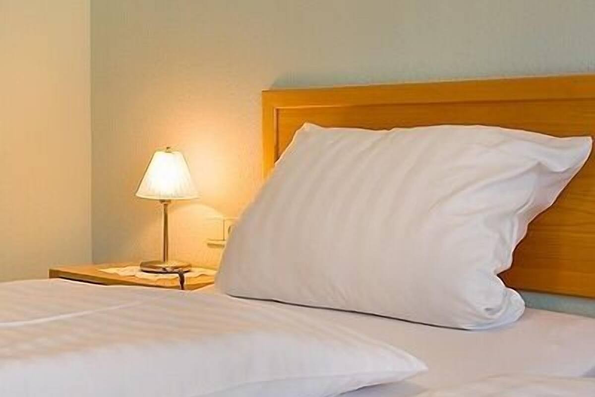 Una habitación de hotel con una cama, una mesita de noche y una lámpara.