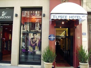 The exterior of the ELYSEE HOTEL with a large glass window displaying a poster, a sign indicating it is a hotel, and the address number 92. - Hôtel Elysée (Lyon)