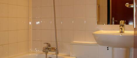 A bathroom with a bathtub, a sink, and a mirror.