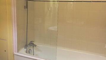 A bathroom with a glass-enclosed shower, a white bathtub, and a toilet.