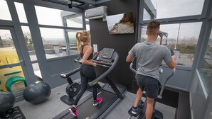 Ein Fitnessstudio mit Laufbändern, Übungsbällen und einem großen Fenster mit Blick ins Freie.