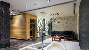 Ein moderner Spa-Bereich mit einer Holzverkleidung, einem schwarzen Ledersofa und einer Steinwand.