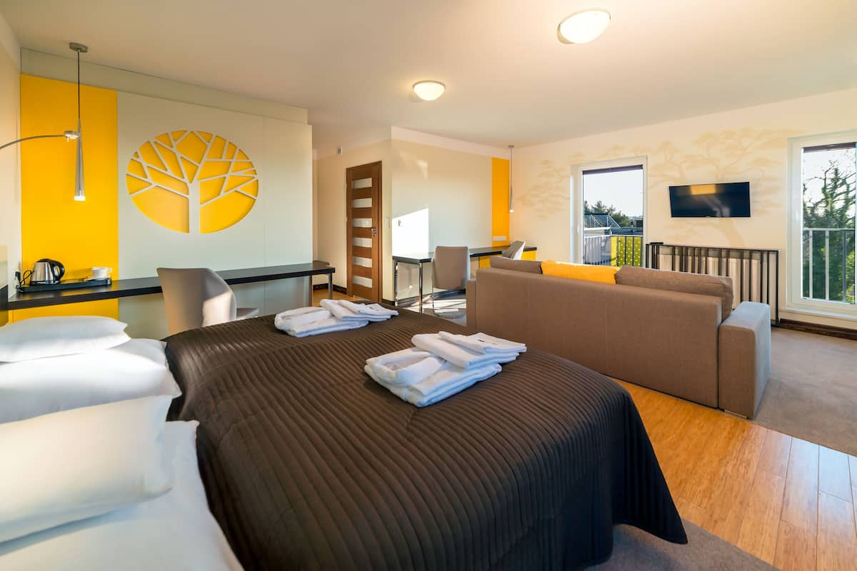 Una habitación de hotel moderna con una cama grande, un sofá, un escritorio y un televisor.