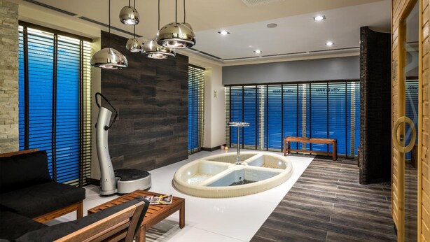 Ein modernes Interieur mit einer zentralen Wasserspiele und einer schwarzen Couch sowie einer hölzernen Bank.