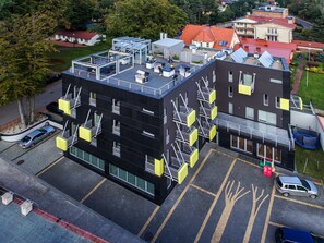En moderne bygning med flere etager, fladt tag og flere balkoner samt en parkeringsplads.