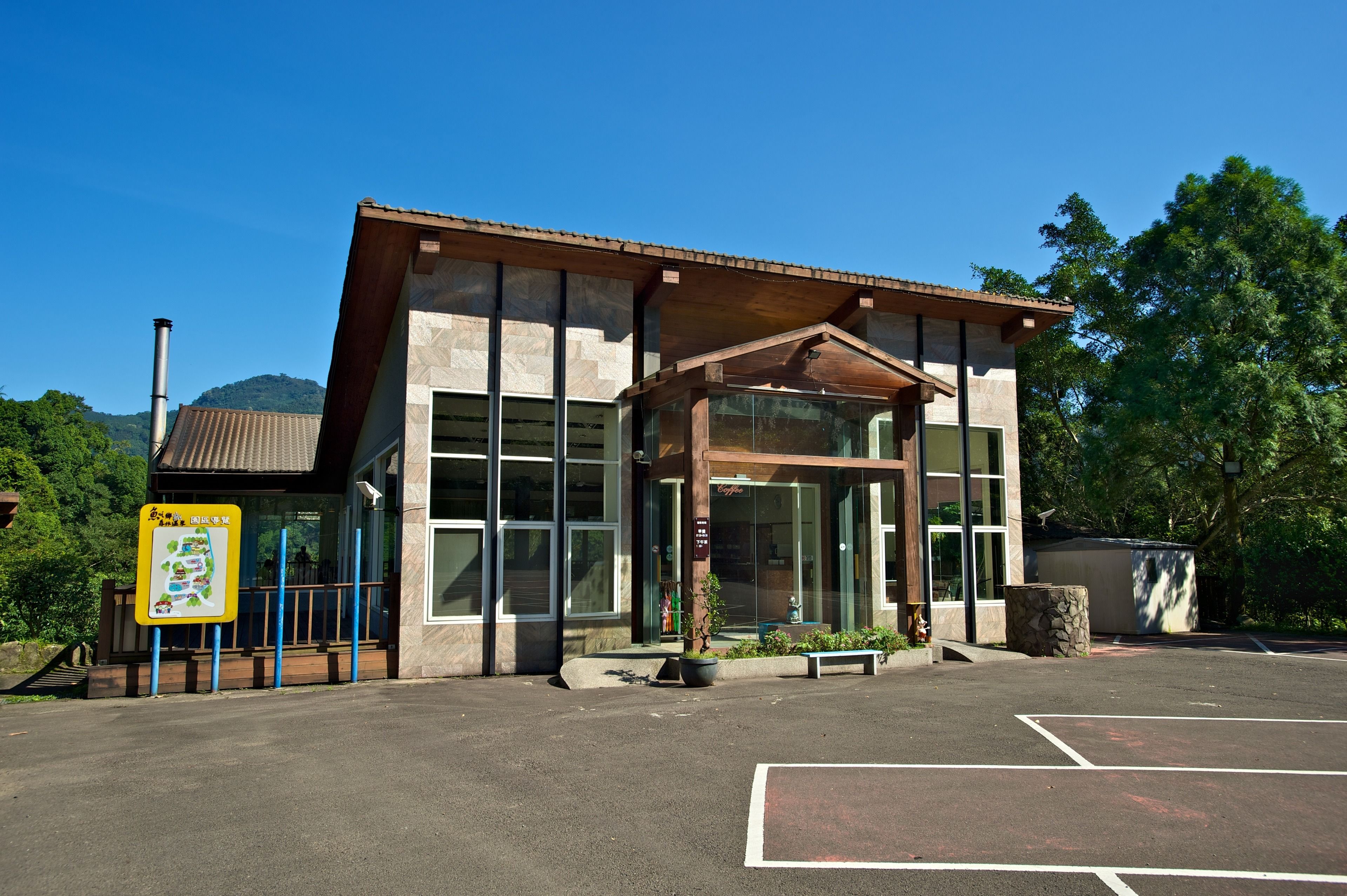 A modern building with large windows, a covered entrance, and a parking lot.