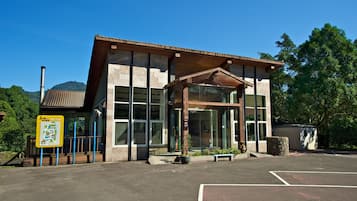 A modern building with large windows, a covered entrance, and a parking lot.
