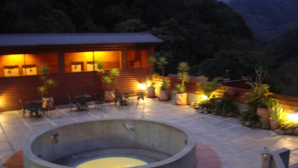 A circular hot tub with a wooden deck, surrounded by potted plants and outdoor furniture. - Hsinchu Bali Forest Hot Spring Resort (Jianshi)