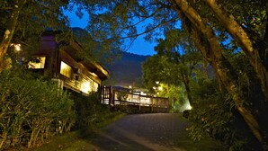 A pathway leading to a wooden cabin surrounded by trees, with a mountain in the background. - Hsinchu Bali Forest Hot Spring Resort (Jianshi)