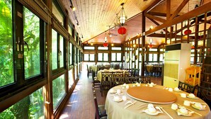 A restaurant with round tables set for dining, large windows, and wooden beams on the ceiling. - Hsinchu Bali Forest Hot Spring Resort (Jianshi)