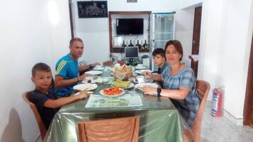 A family dining at a table with a green tablecloth, surrounded by chairs.